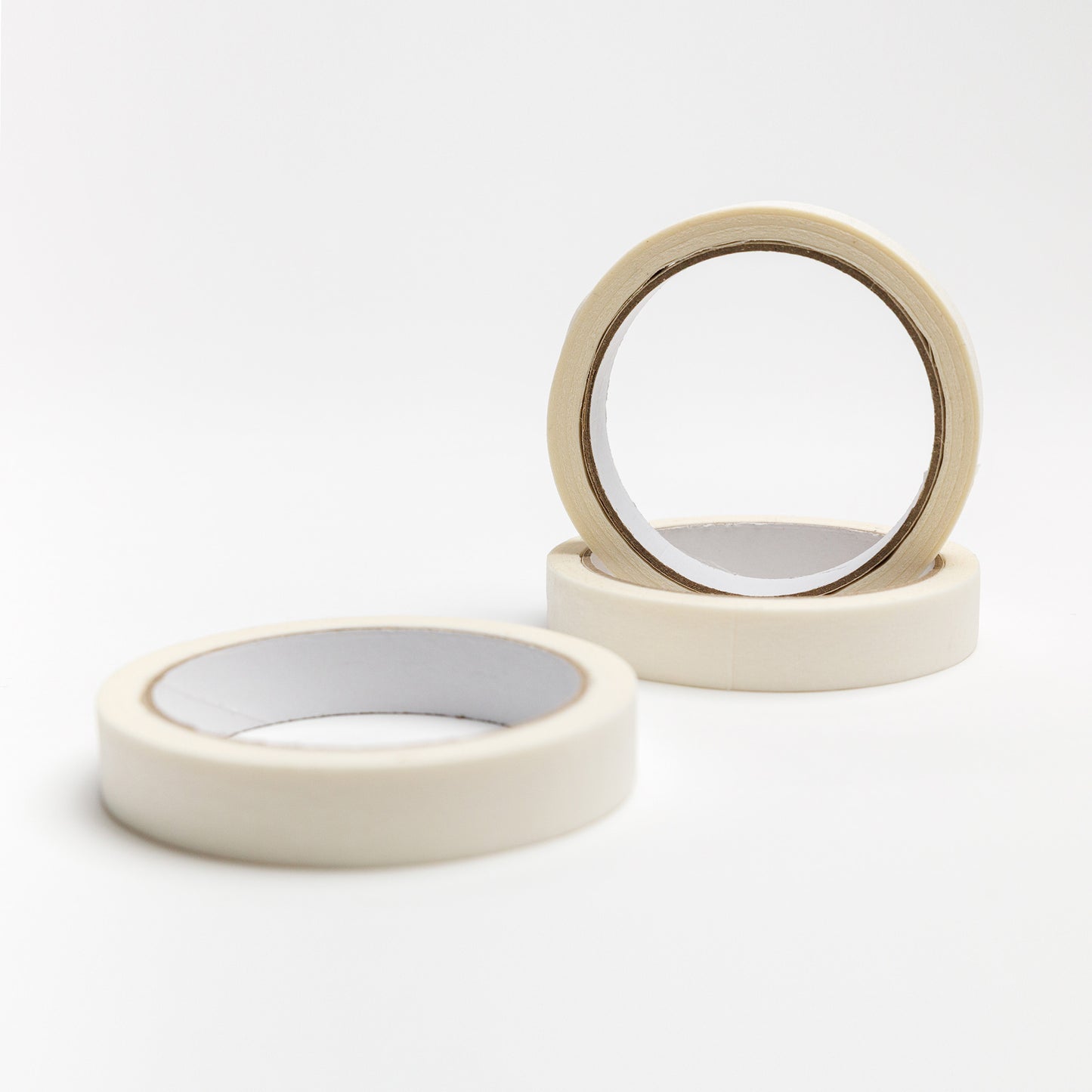 Three rolls of artist tape, one standing and two lying flat on white surface