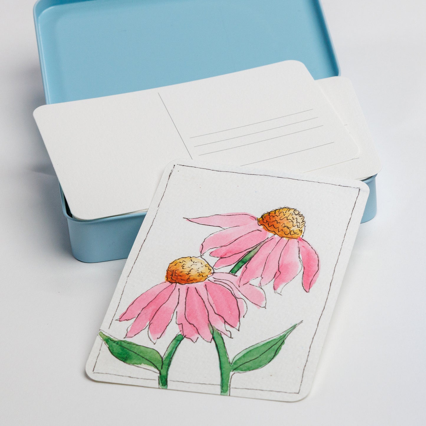 Close up of postcard tin with an example of a painted postcard