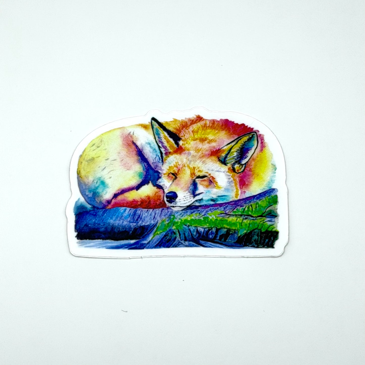 Sticker of a colorful fox sleeping on a rock with grass, on a white background