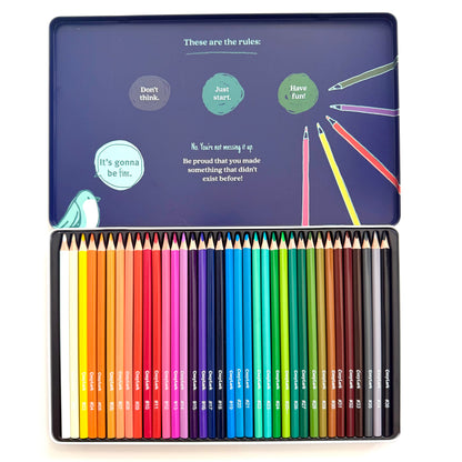 A 36-piece colored pencil set in a square metal tin, shown open against a white background. The top lid features a dark blue background with whimsical illustrations and text, while the bottom tray displays the neatly arranged colored pencils in a rainbow of shades.
