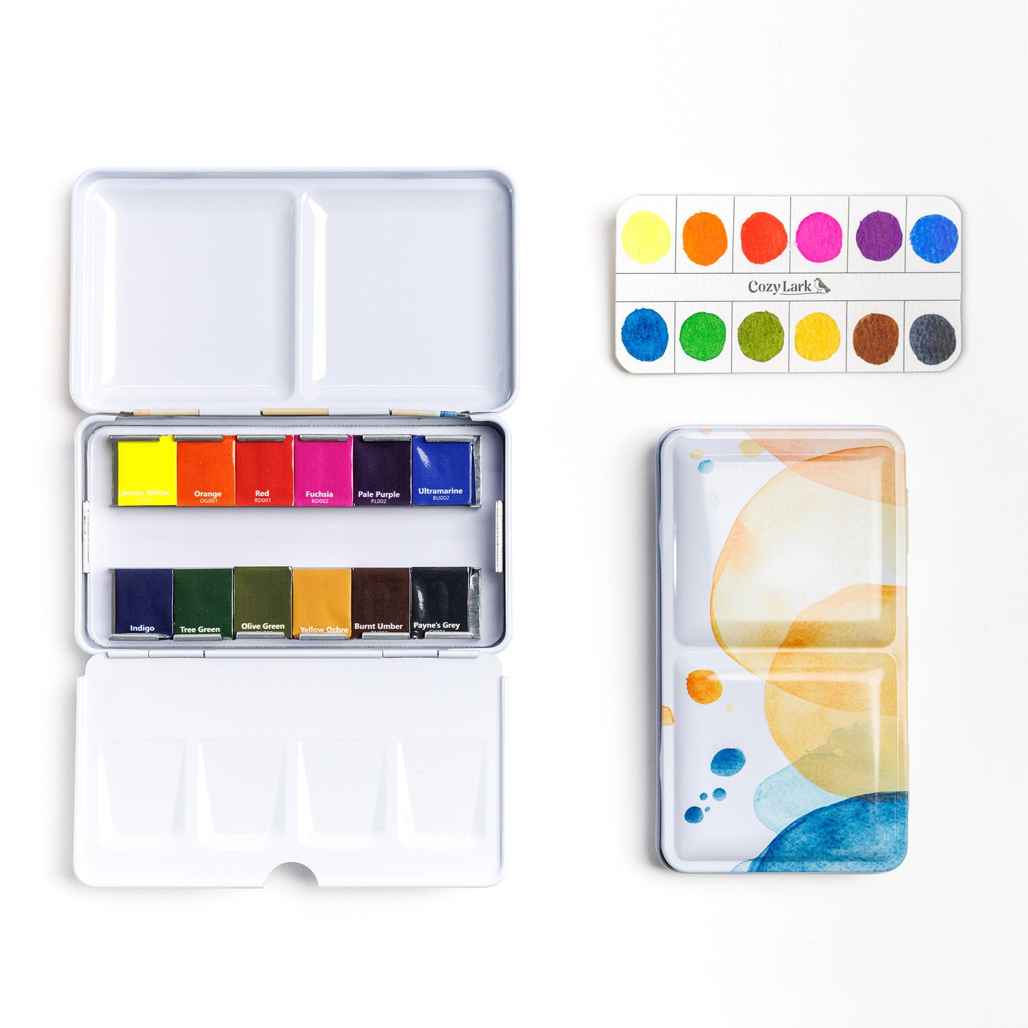 Cozy Lark 12‑color watercolor paint set tin open to rainbow pans with printed color swatch card and patterned lid beside it