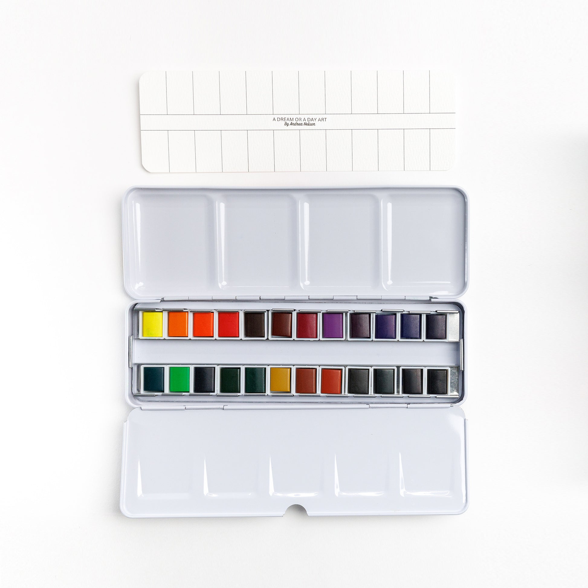 Cozy Lark 24‑color watercolor paint set tin open to two rows of pans with blank color swatch card above on white background