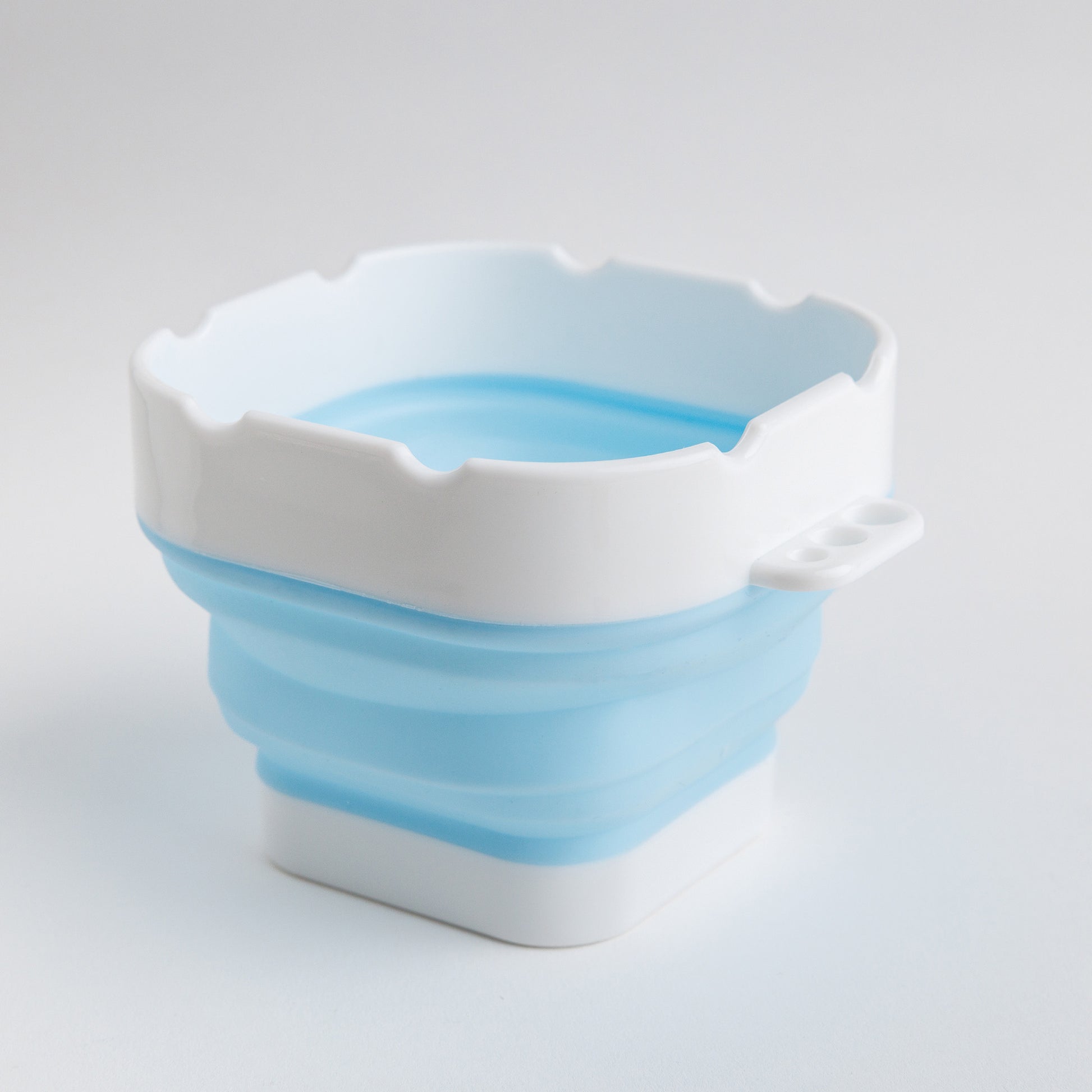 Light blue and white collapsible silicone water cup for watercolor painting on white background