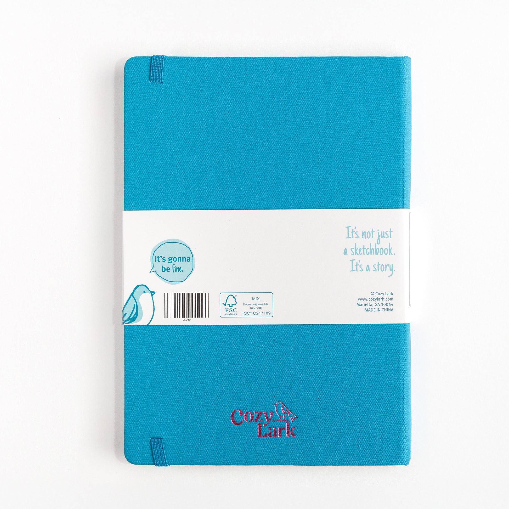 Blue hardcover essential sketchbook with Cozy Lark imprint in pink centered at the bottom on a white background