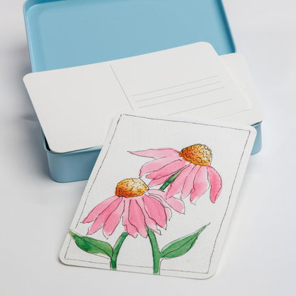 Close up of postcard tin with an example of a painted postcard 