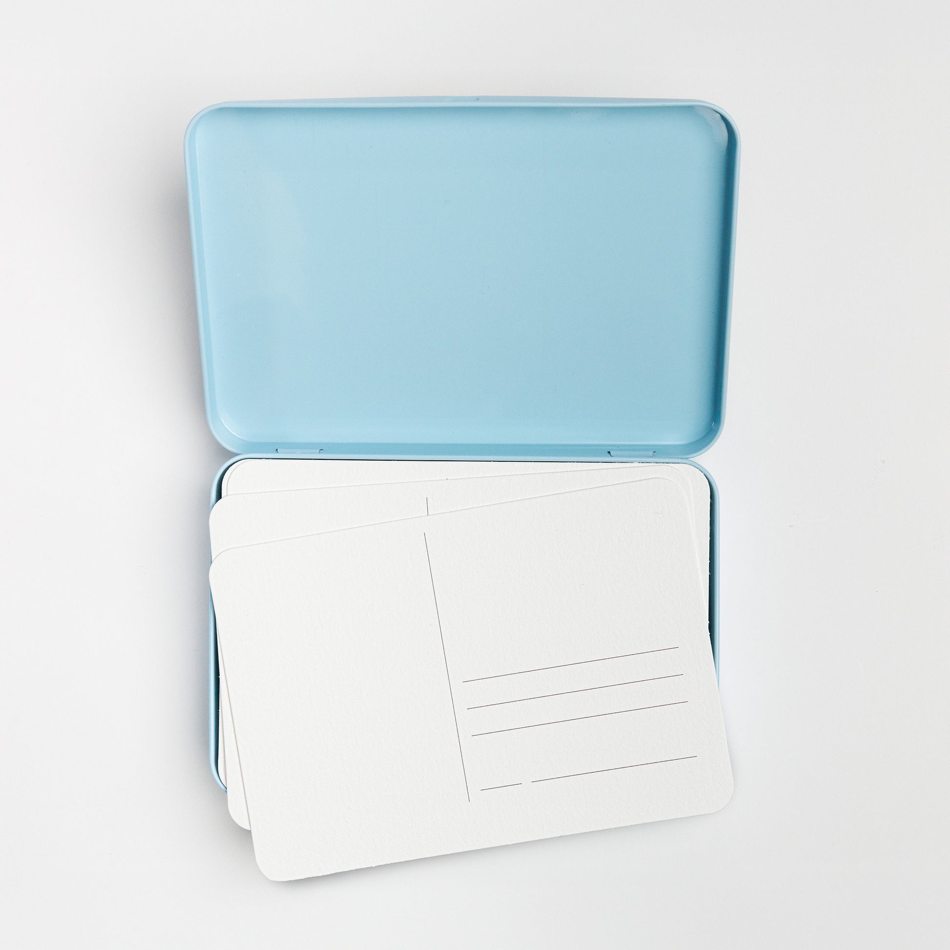 Open postcard tin with blank postcards inside.