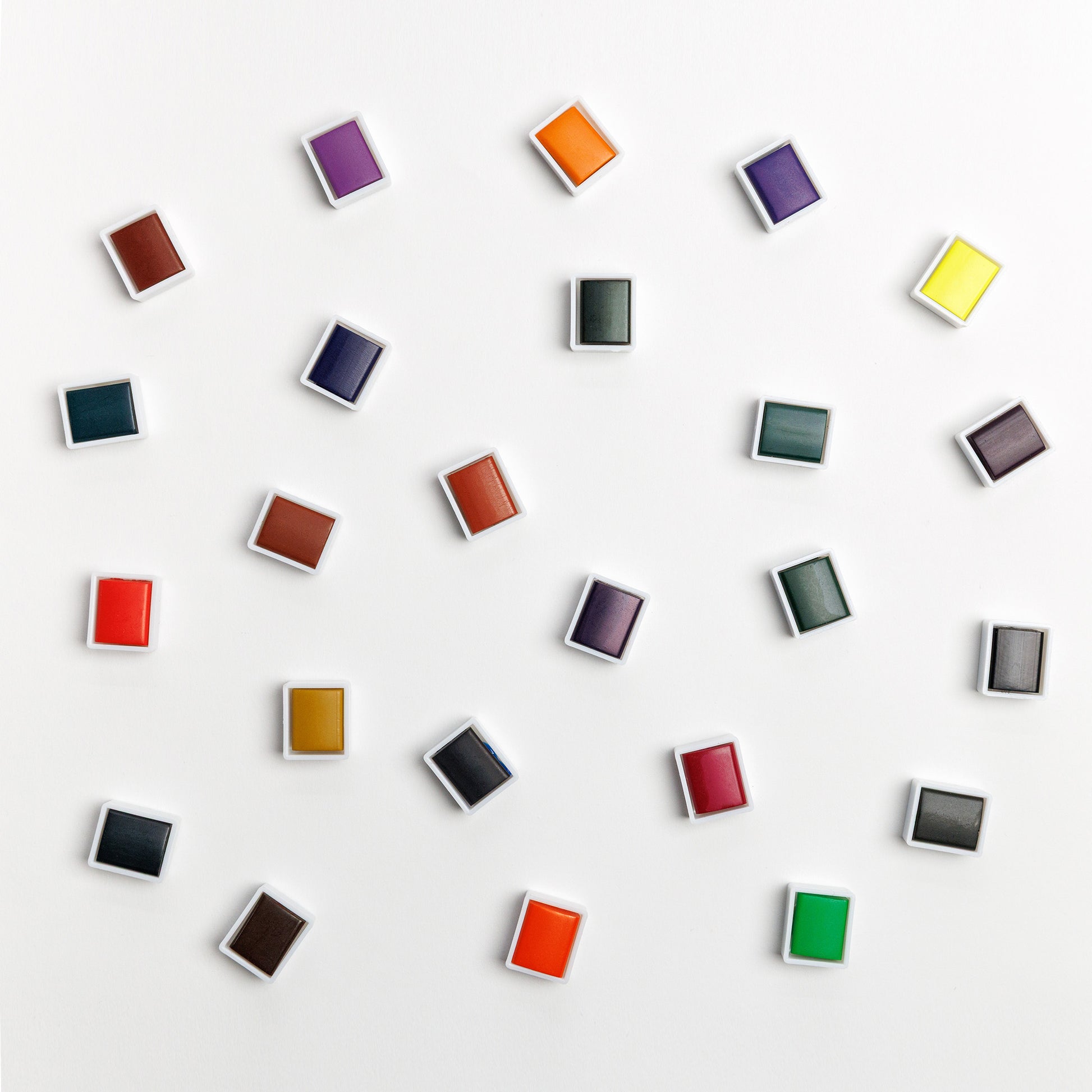 Array of individual water color paint pans on white background