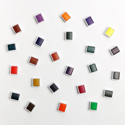Array of individual water color paint pans on white background