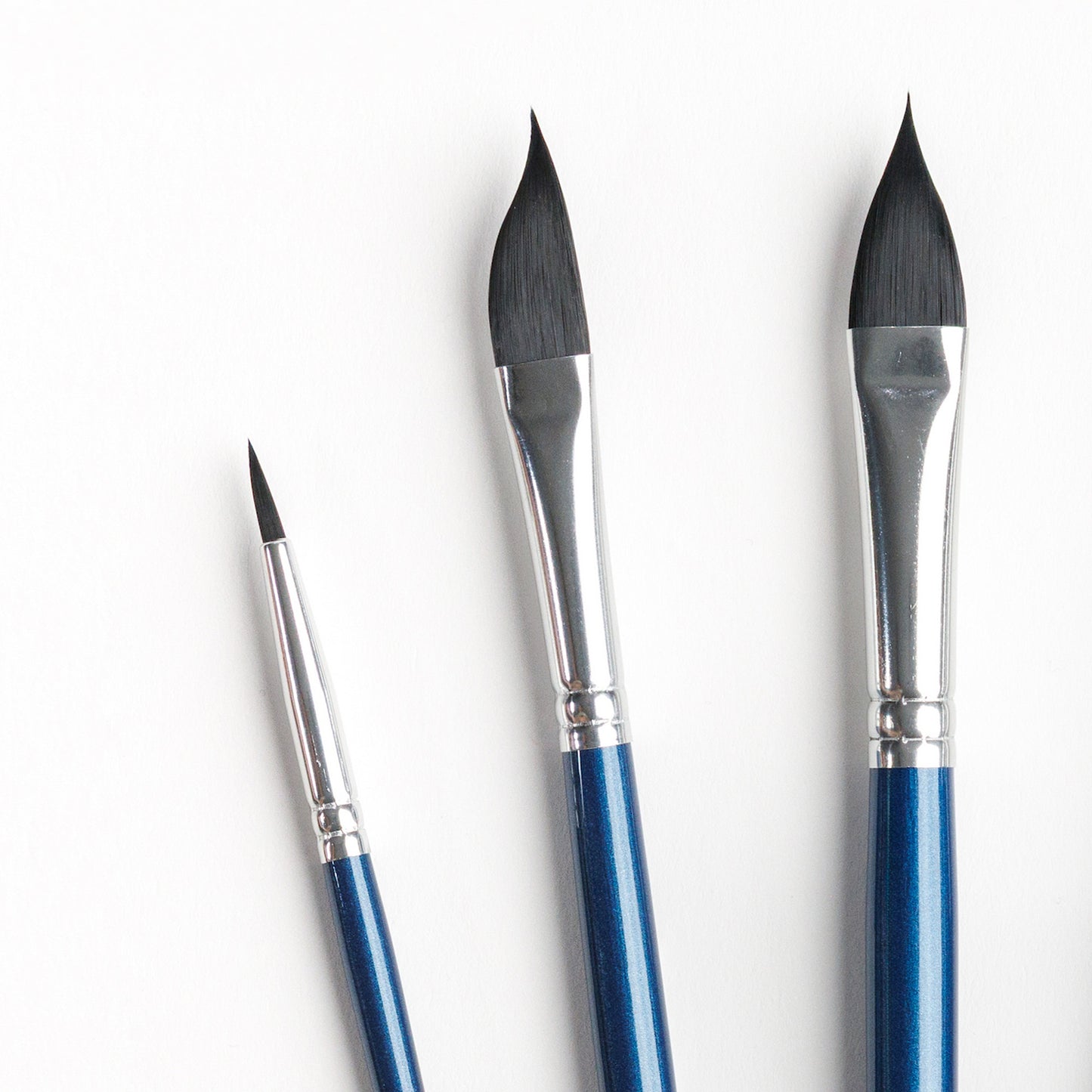 Close up of three specialty brushes including size 2 round, size 6 dagger, and size8 cat's tongue brushes. 