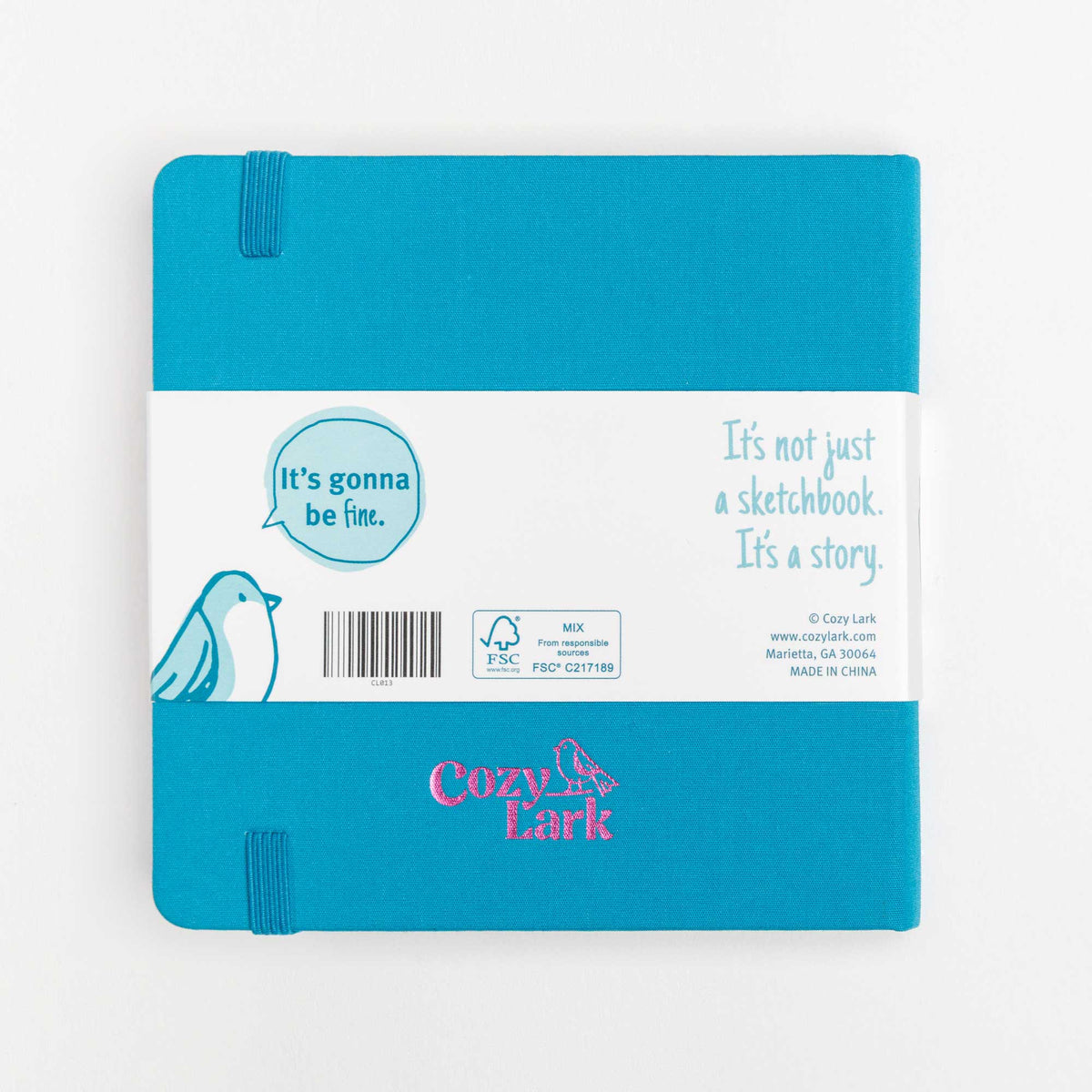 Back view of teal cloth hard cover travel notebook with bellyband and Cozy Lark logo embossed in pink centered near the bottom edge on a white background.