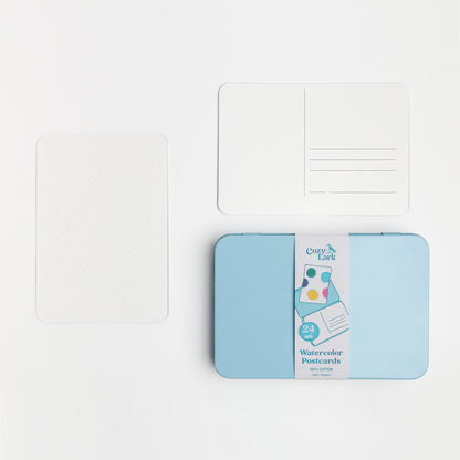 Pack of watercolor postcards with a blue tin and showing the front and back of the blank postcards.